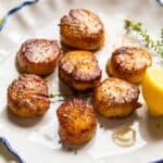 Close up of golden brown seared scallops with a lemon.