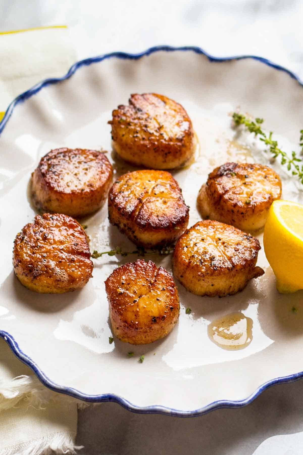 Close up of golden brown seared scallops with a lemon.
