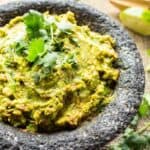 Spicy guacamole in a molcajete garnished with cilantro.