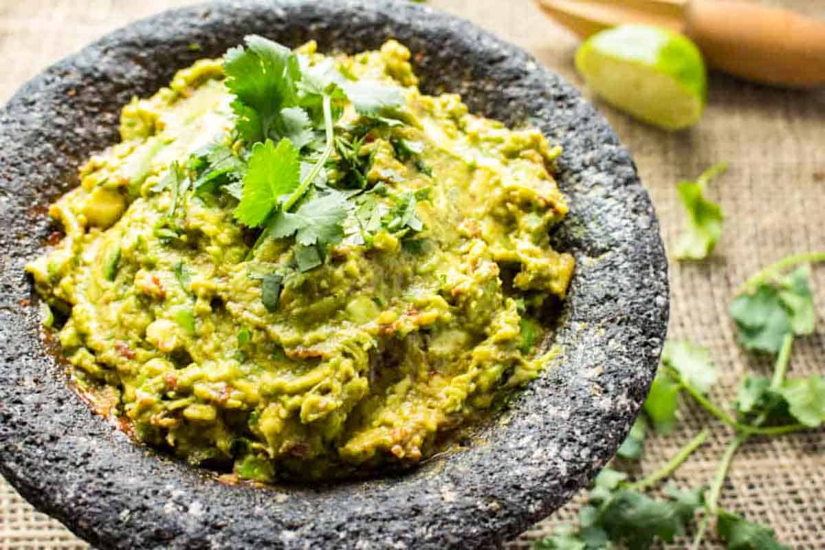 Spicy guacamole in a molcajete garnished with cilantro.