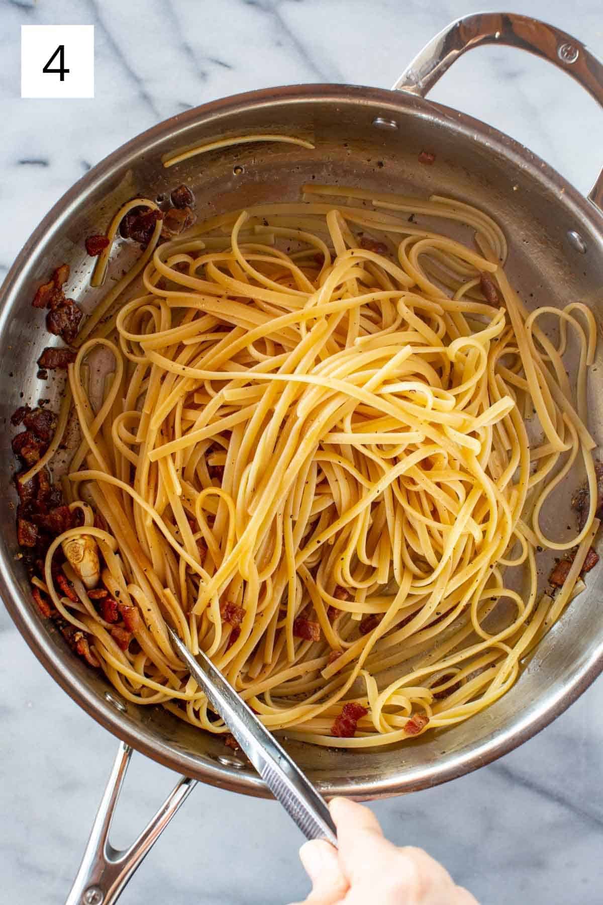 Linguine being tossed in a pan with bacon.