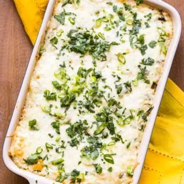 Overhead shot of a rectangular casserole dish with melted cheese and scallions on top.