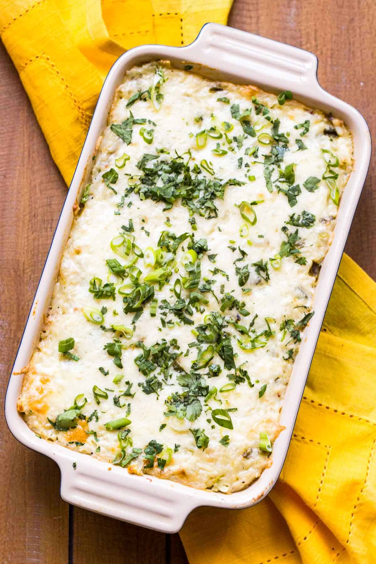 Overhead shot of a rectangular casserole dish with melted cheese and scallions on top.