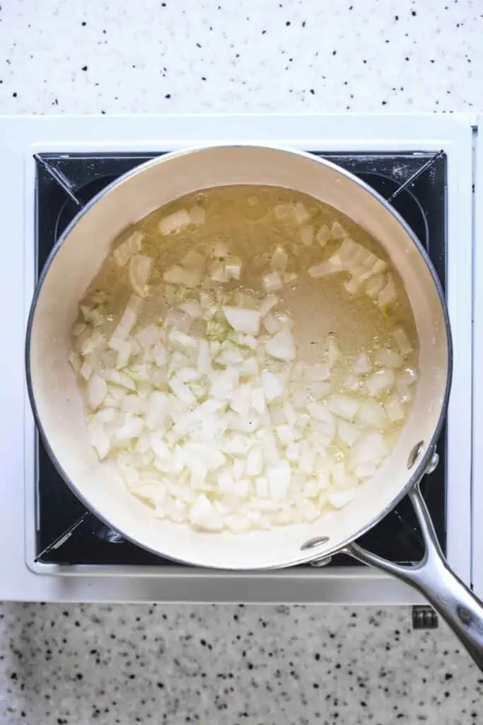 A pot of onions being sautéed in olive oil.