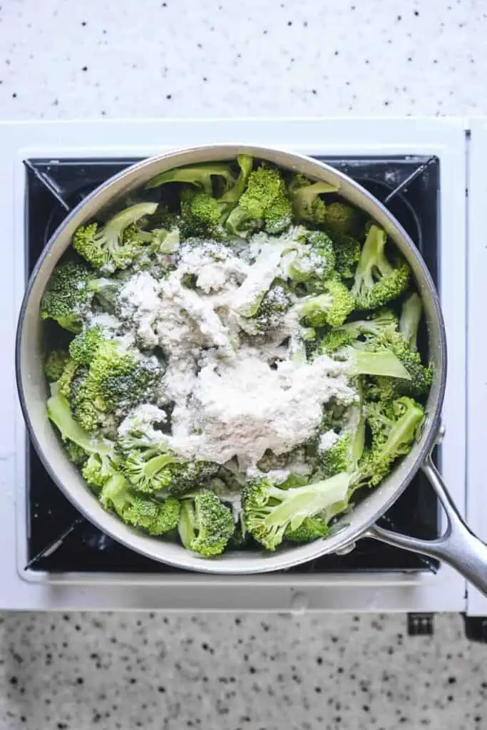 A pot with broccoli and flour sprinkled over the top.