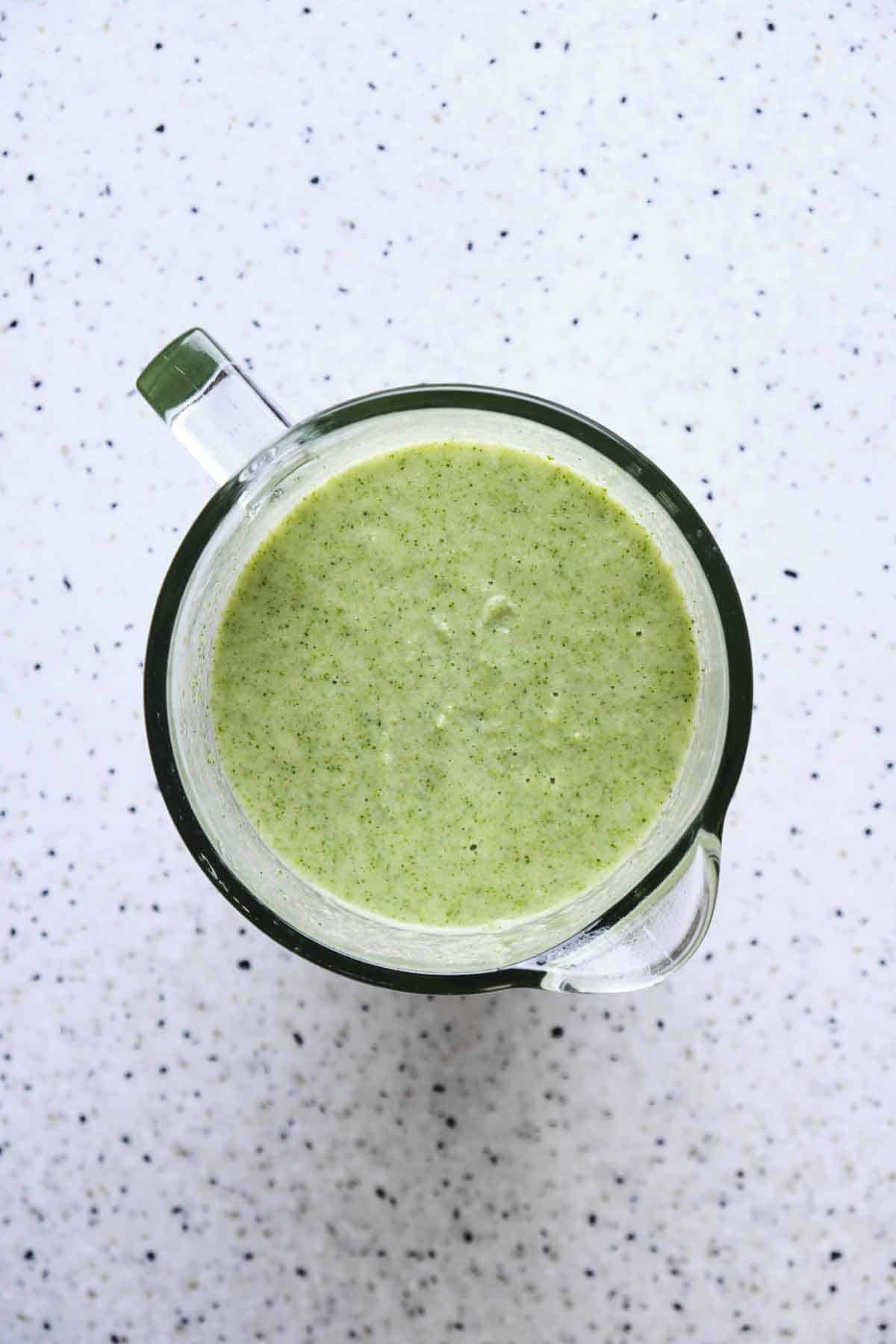Top view of a blender jar full of broccoli soup.