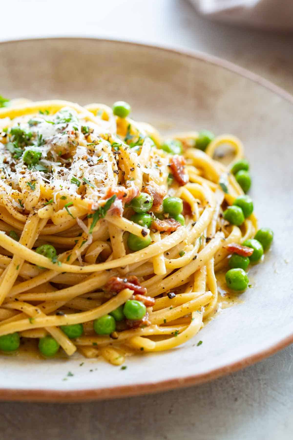 Close up of pasta alla carbonara with peas and bacon.