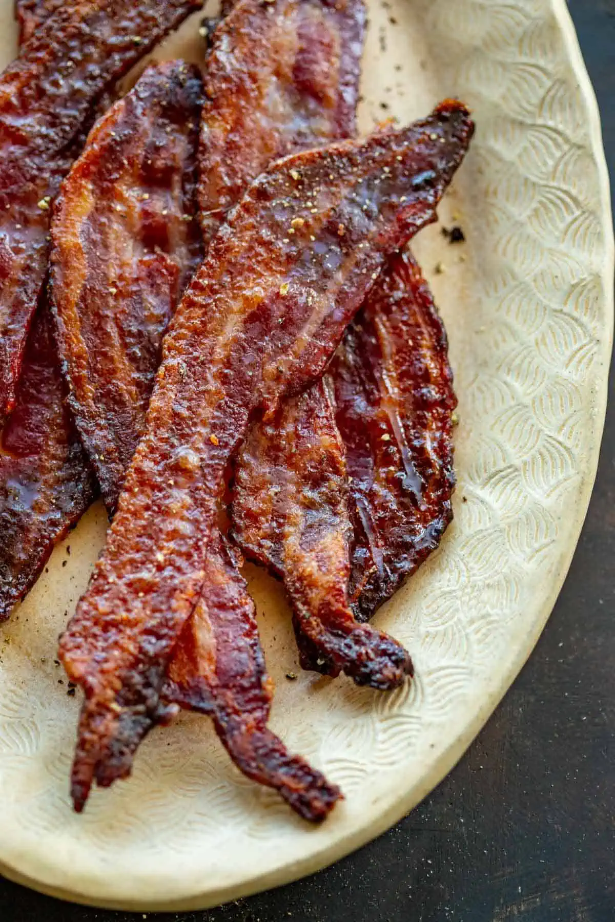 Close up top view of a plate of candied bacon. 