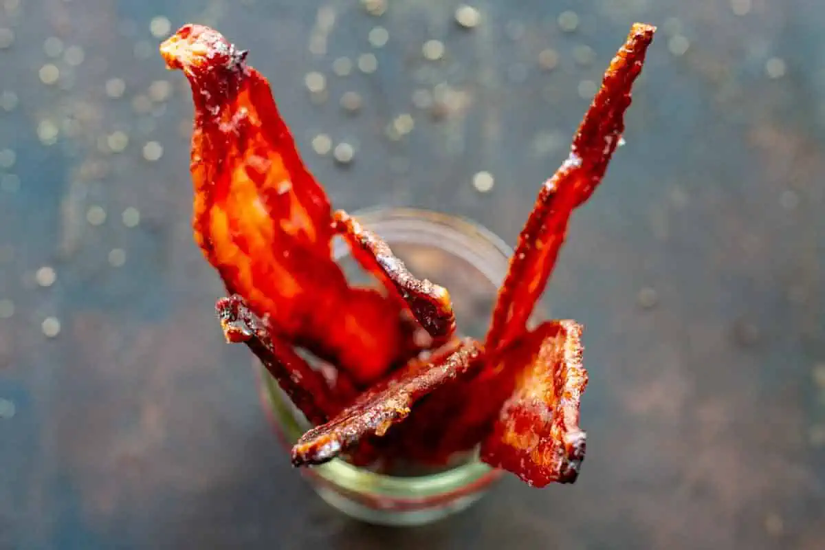 Top view of a mason jar filled with candied bacon strips.