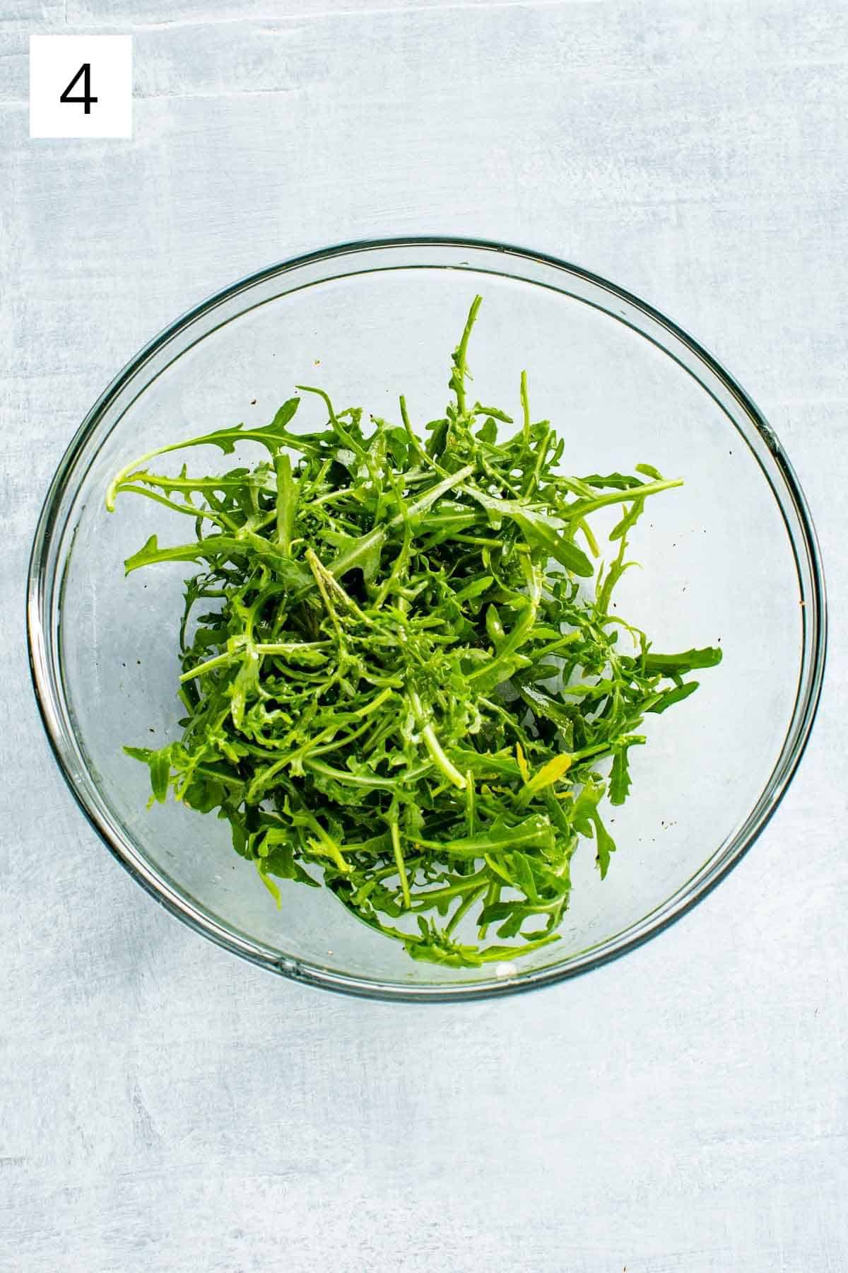 A glass bowl filled with arugula.