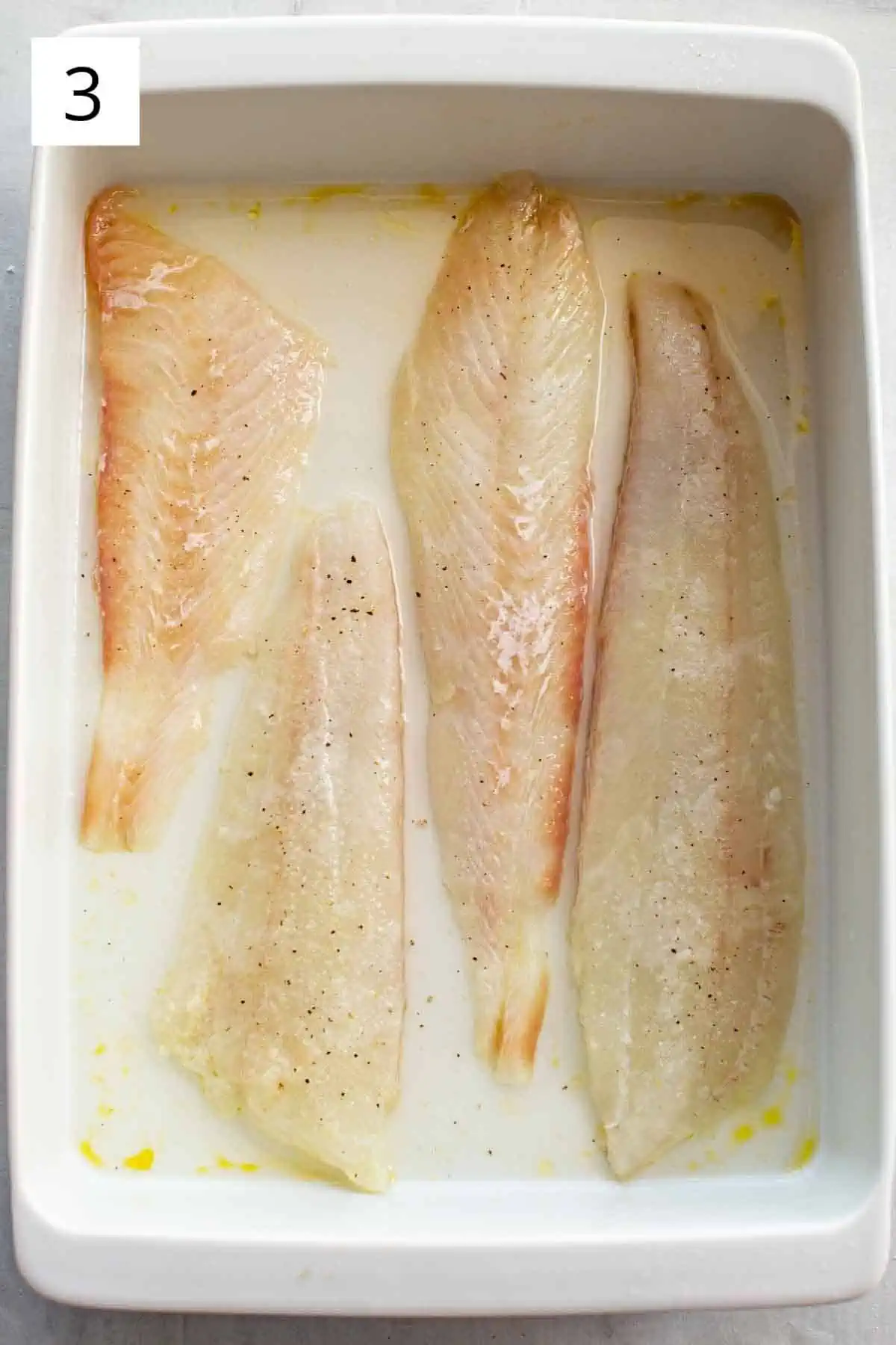 Raw flounder fillets in a baking dish.
