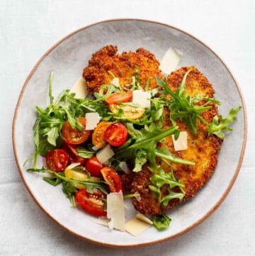 Overhead shot of a plate of crispy chicken Milanese with tomato arugula salad.