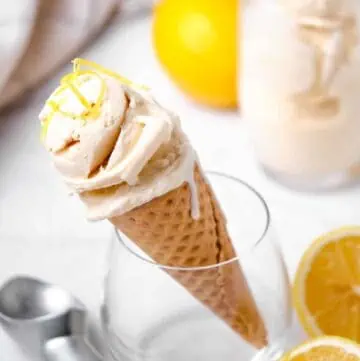 A glass holding an ice cream cone with lemon ice cream.