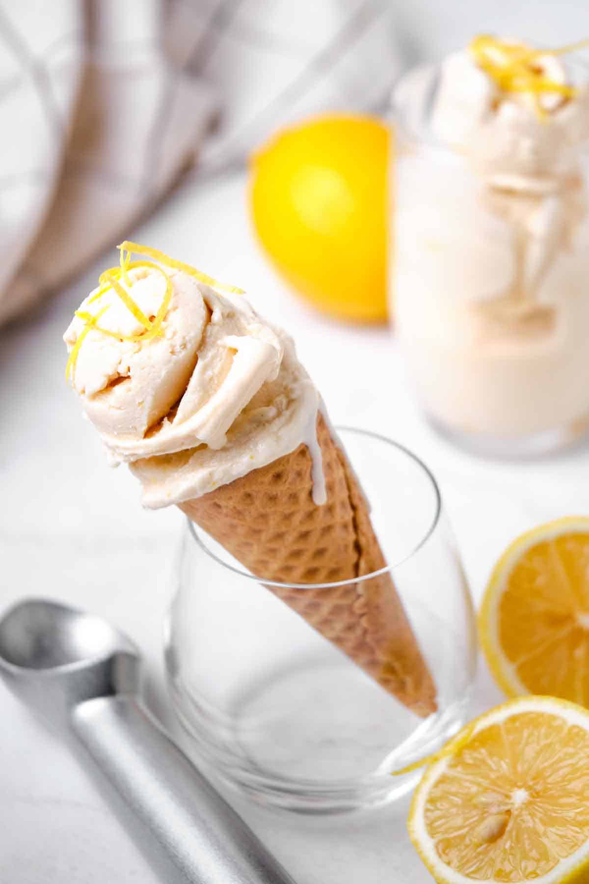 A glass holding an ice cream cone with lemon ice cream.