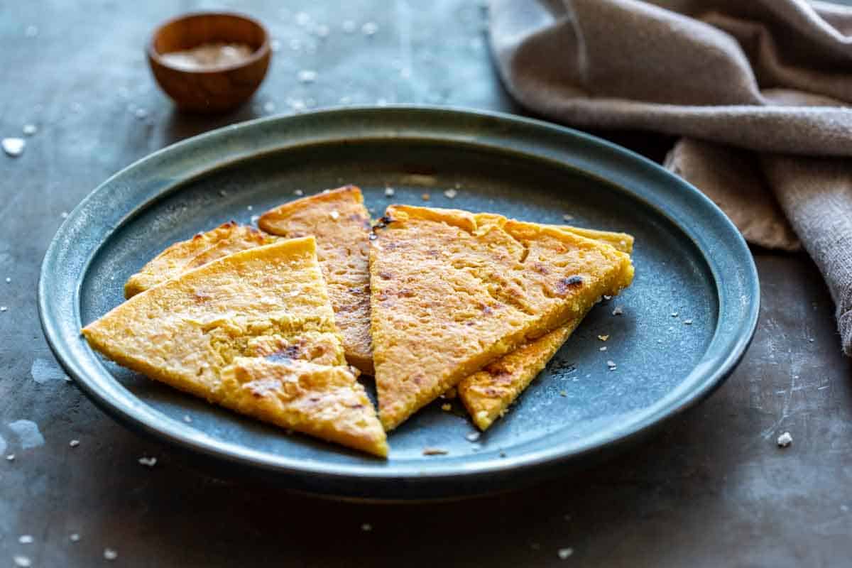 Four pieces of an Italian chickpea flatbread on a blue plate.