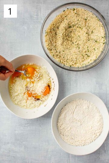 3 bowls, one with flour, one with an egg mixture, and one with a breadcrumb mixture.