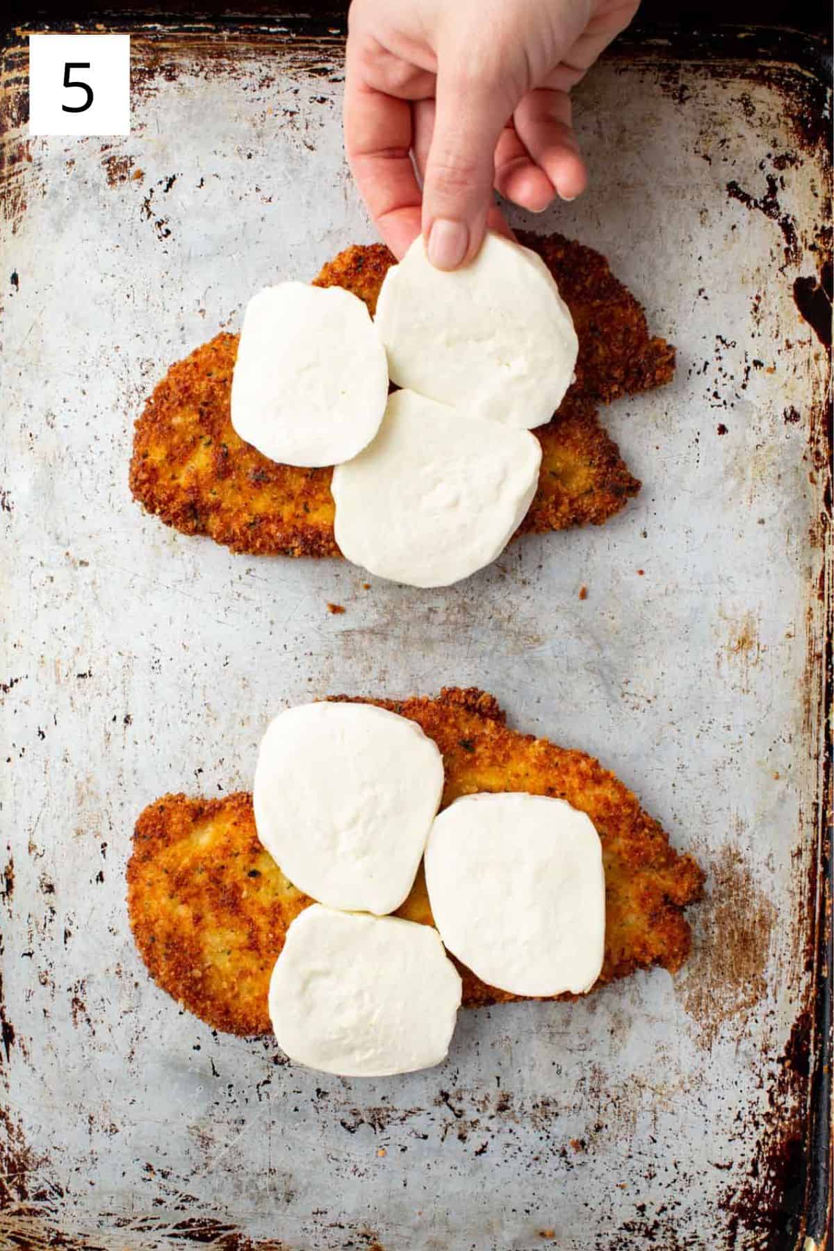 Adding freshly sliced mozzarella to fried chicken before baking.