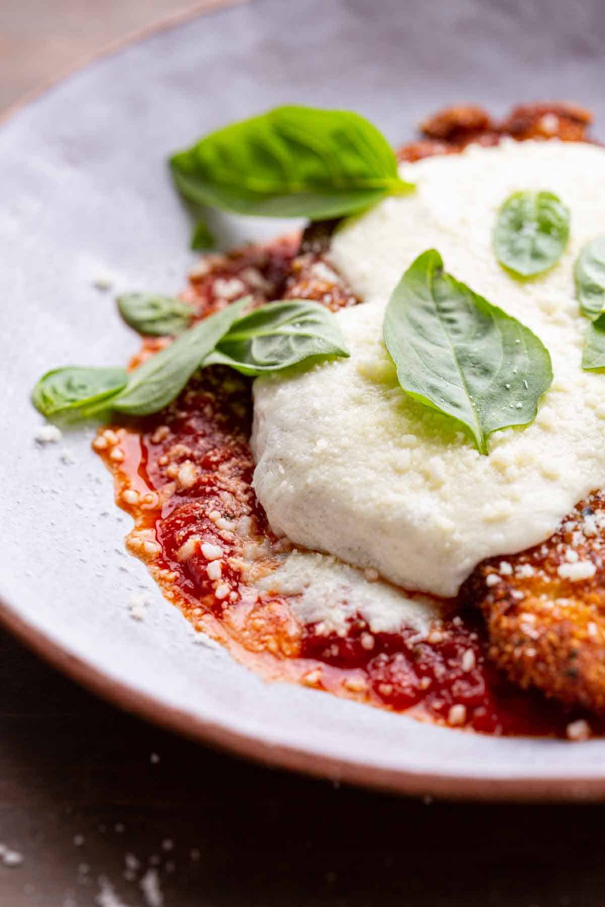 close up of chicken parmesan baked and topped with fresh basil