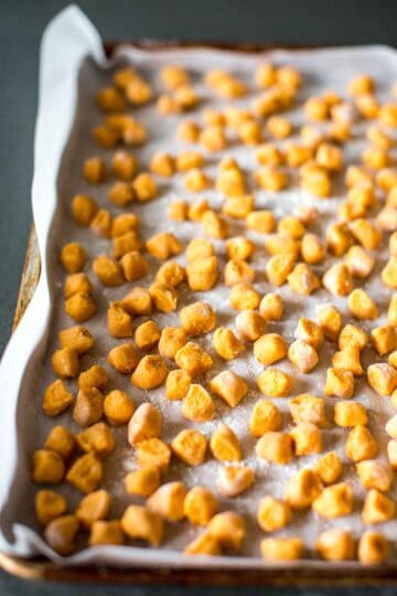 Raw homemade gnocchi on a sheet pan lined with parchment paper.