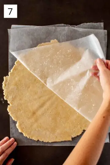 Removing layer of wax paper from rolled out dough. 