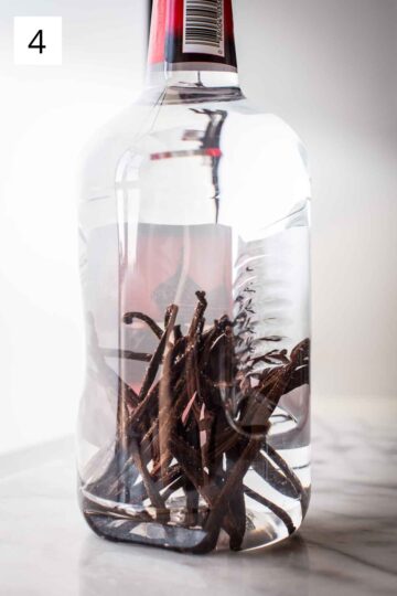 Making homemade vanilla extract in a large vodka bottle.