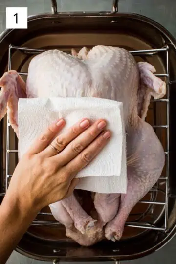 Patting the turkey dry with a paper towel.