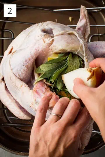 Stuffing the cavity of the bird with lemon, onion, garlic, and herbs.