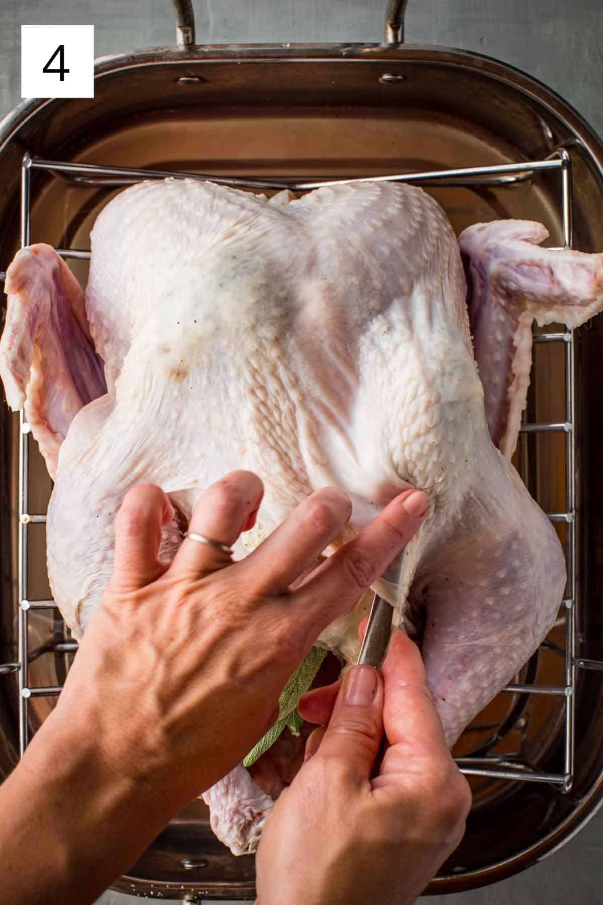 Distributing the butter mixture underneath the turkey skin with a spoon.