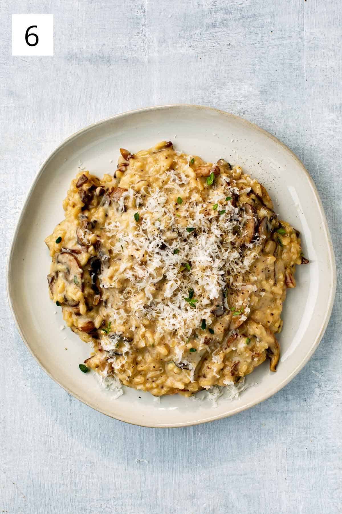 Mushroom risotto on a stoneware plate, topped with fresh parmesan cheese. 