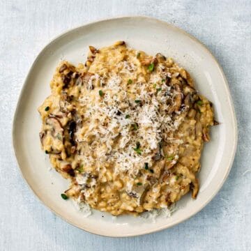 Overhead shot of a plate of mushroom risotto topped with grated cheese.