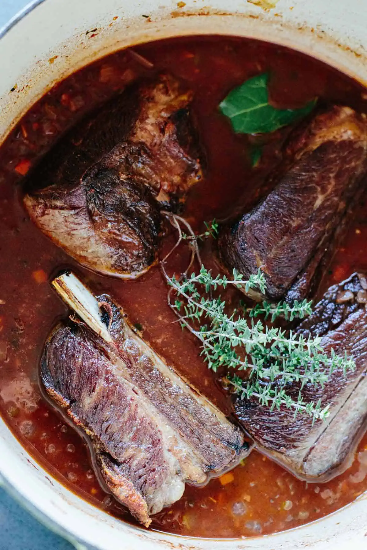 Herb infused short ribs in a large pot.