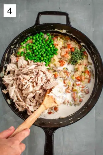 Shredded turkey, peas and cream being stirred into vegetables and gravy.