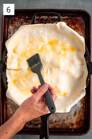 Brushing egg wash over a puff pastry crust.