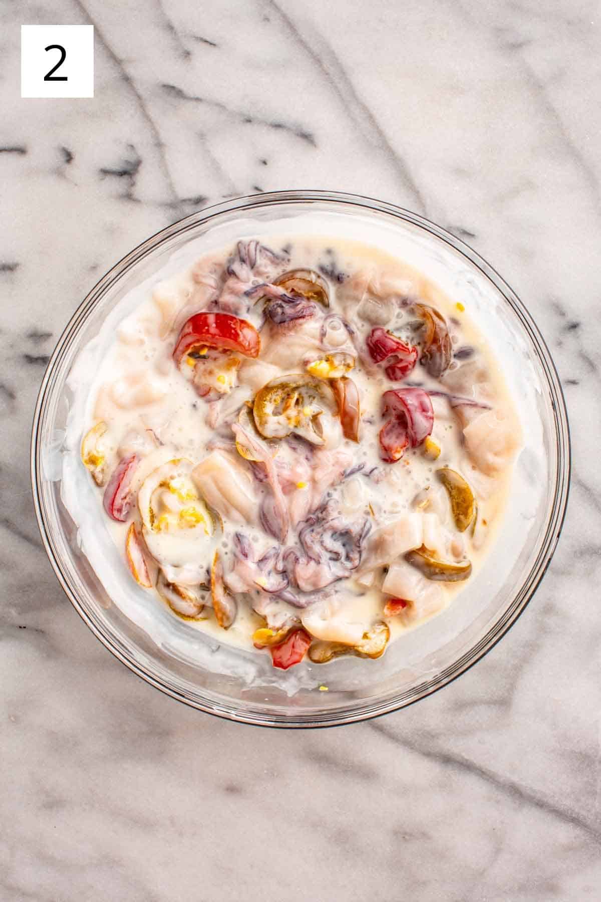 Mixing cherry peppers and buttermilk with calamari pieces.