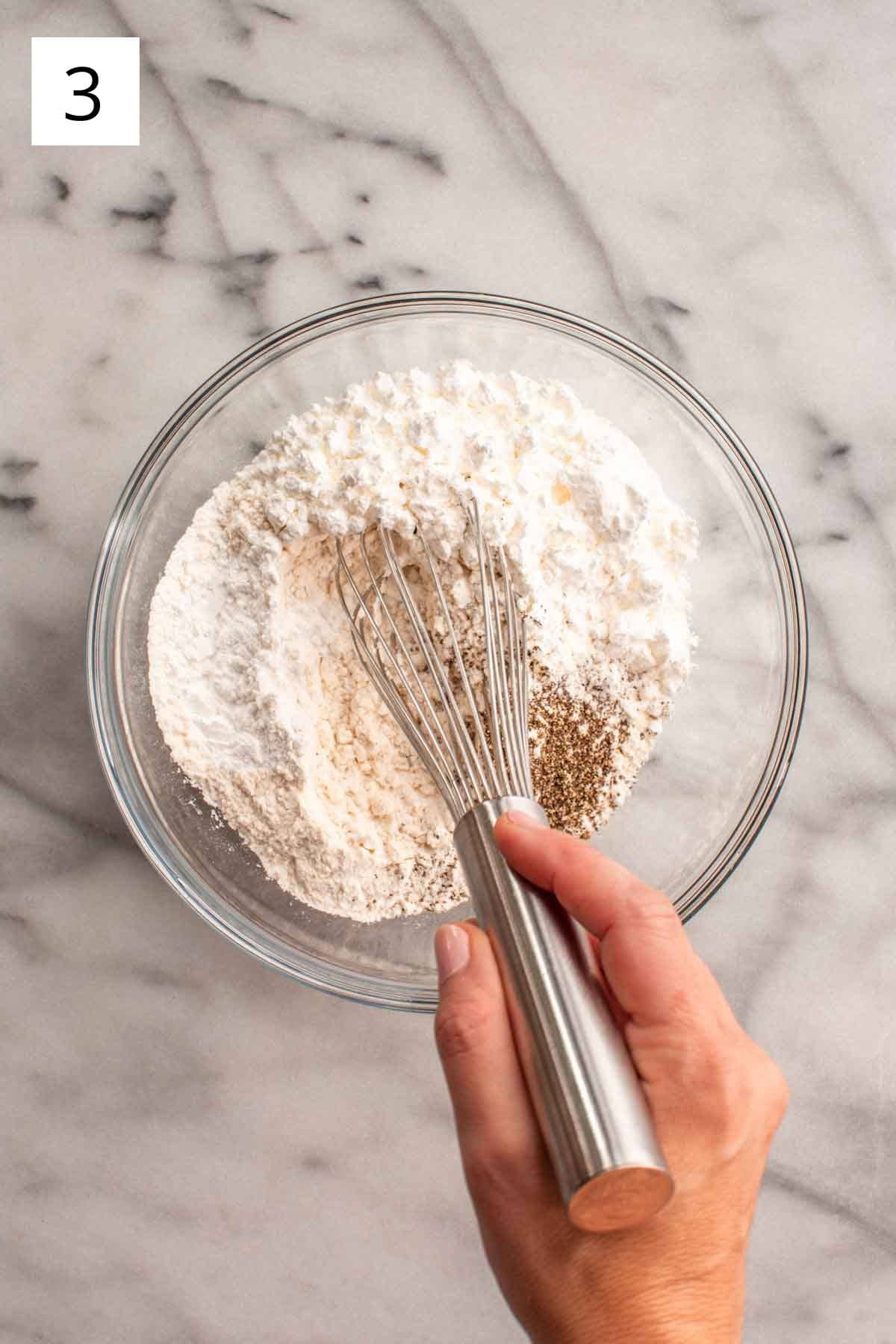 Whisking togther dry ingredients in a clear bowl.