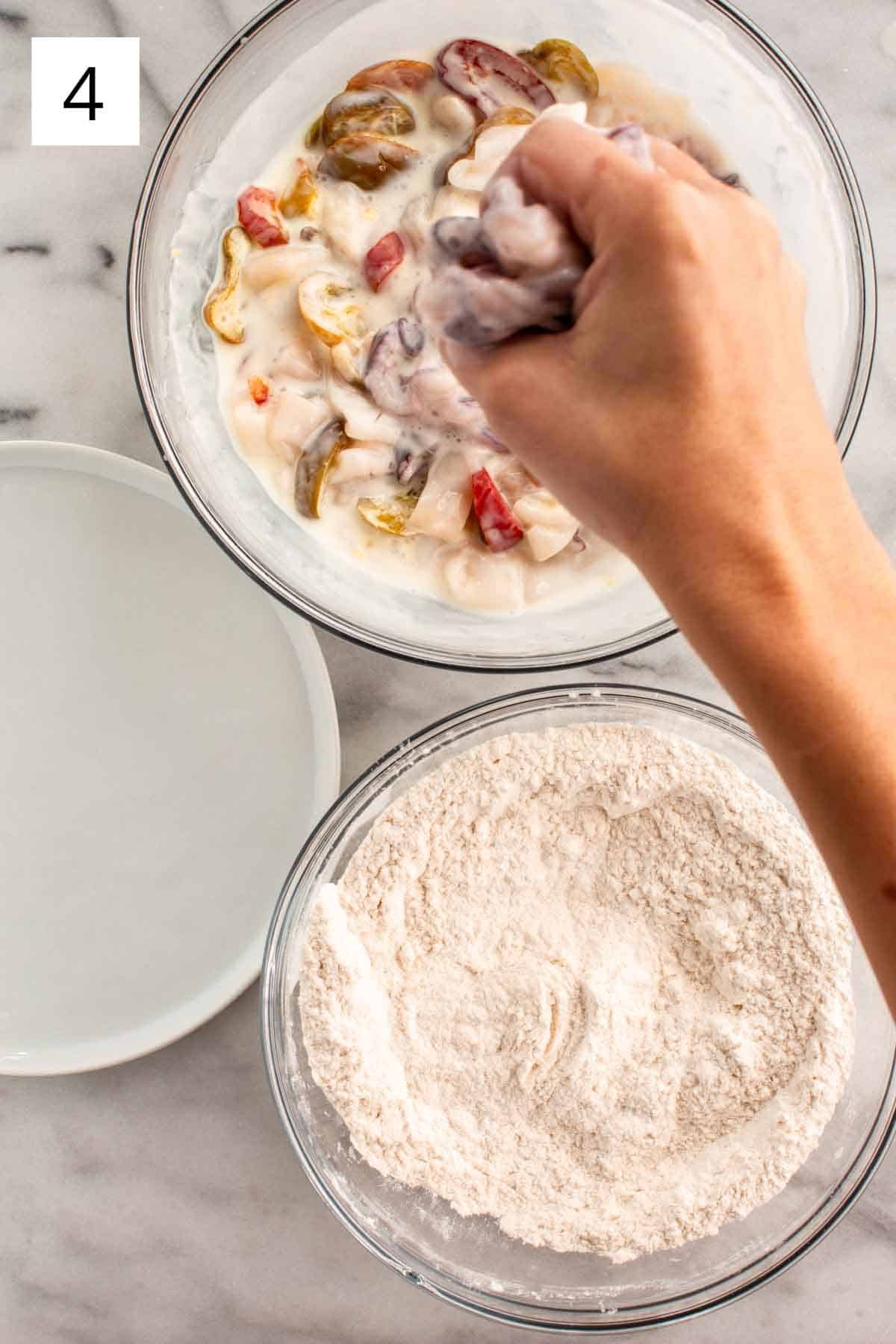 Letting excess buttermilk mixture drain off of a handful of calamari.