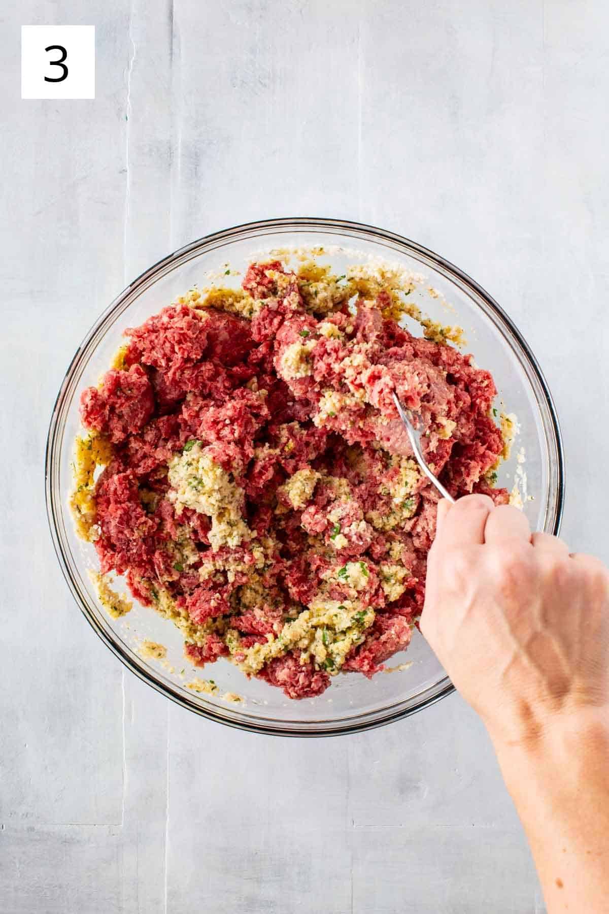 Adding ground meat to meatball mixture.