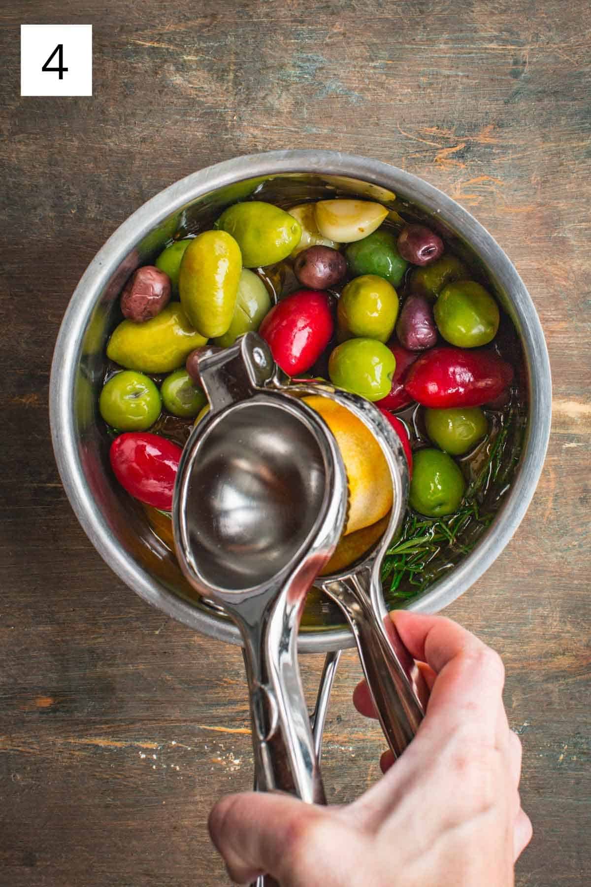 A citrus juicer juicing lemons into a pot of olives.