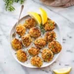 A plate of baked stuffed clams with lemons and a cocktail fork.