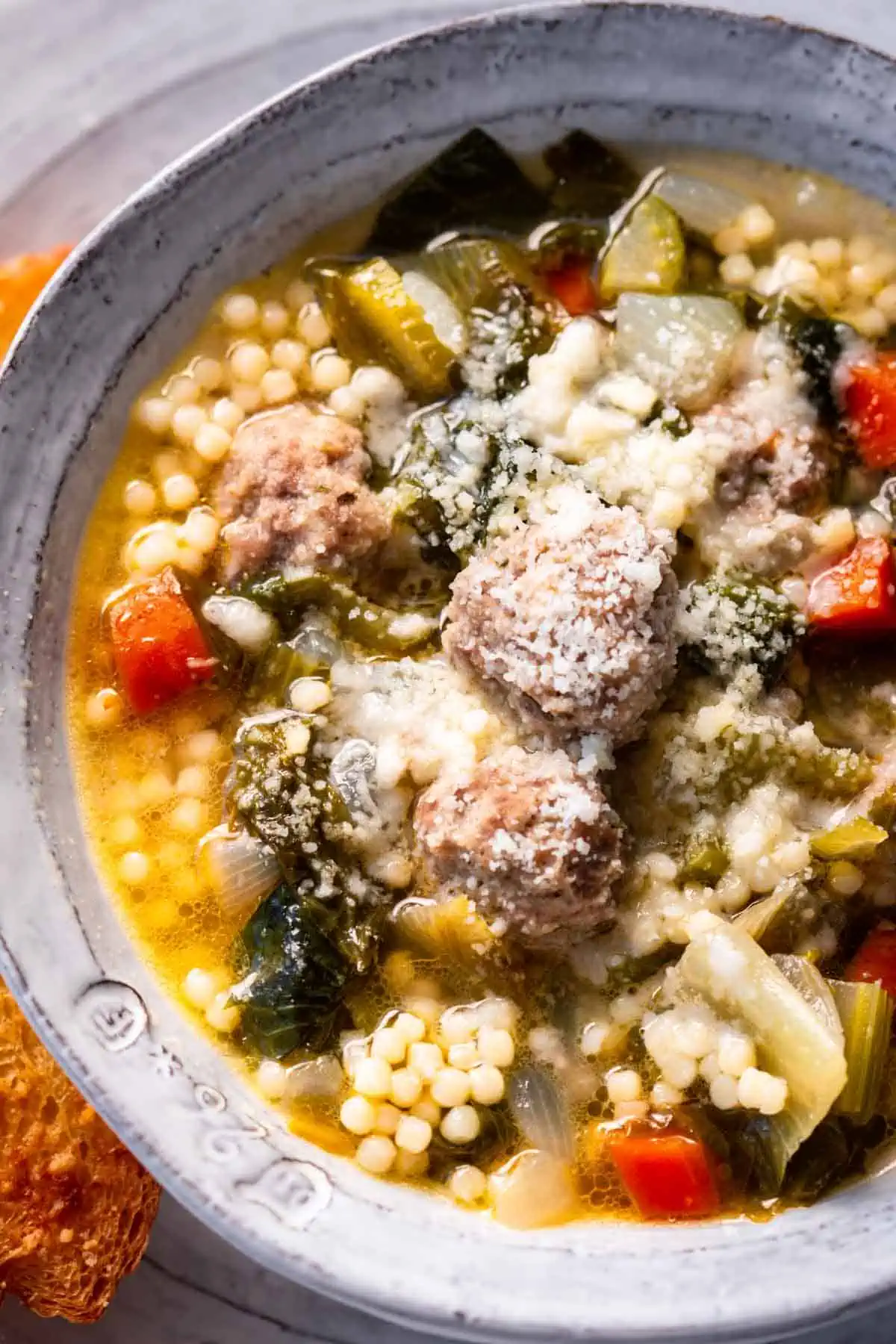 Italian wedding soup in a bowl, sprinkled with cheese.
