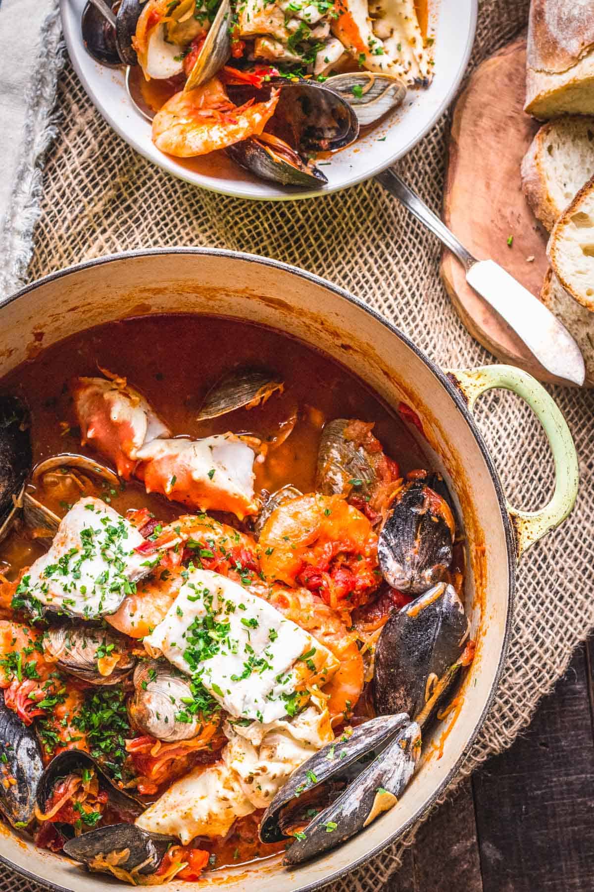 A large pot of seafood stew with a bowl of shells.