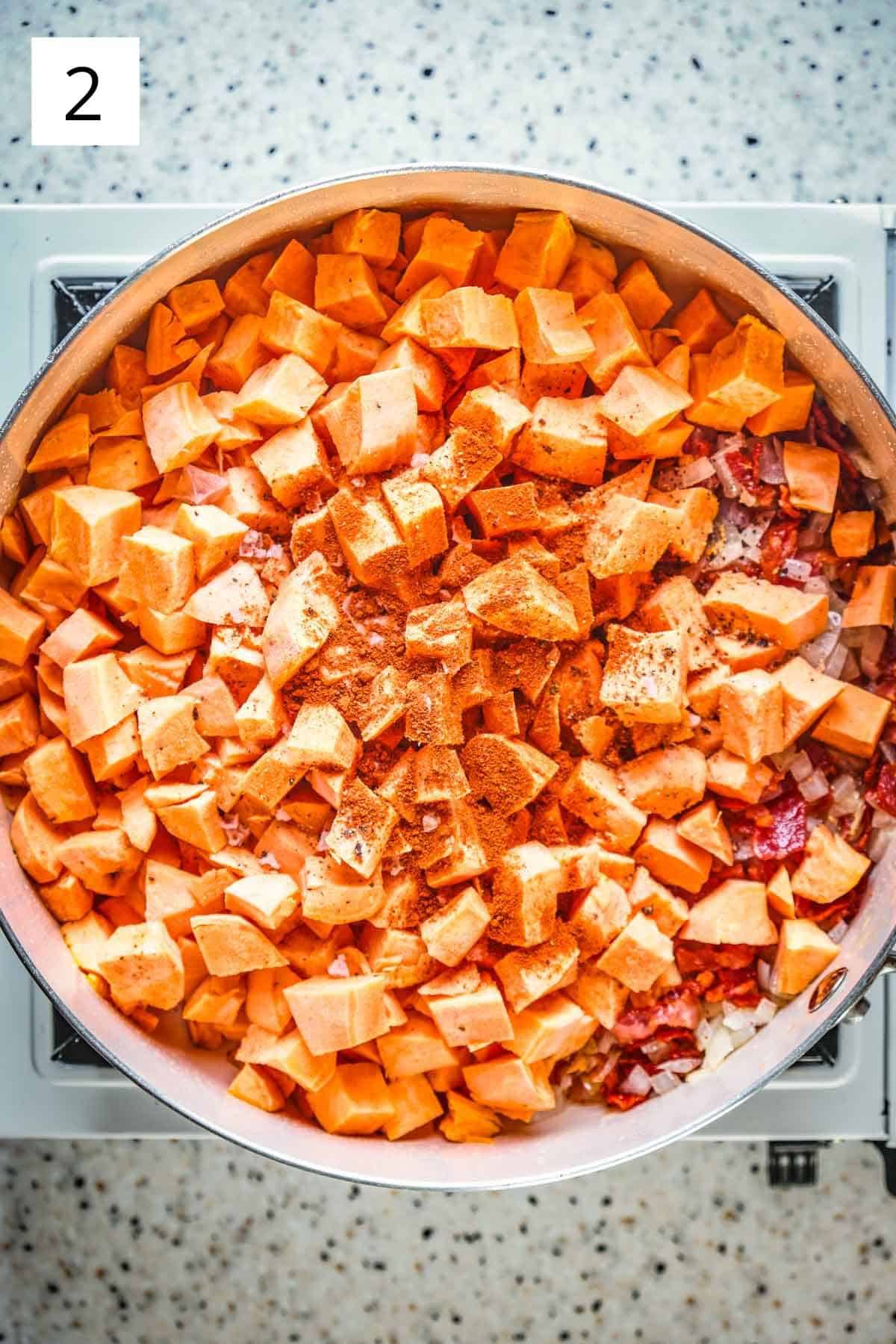 Raw sweet potatoes and spices in a frying pan with bacon.
