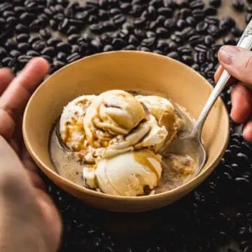 Hands cupping a bowl of affogato with a spoon.