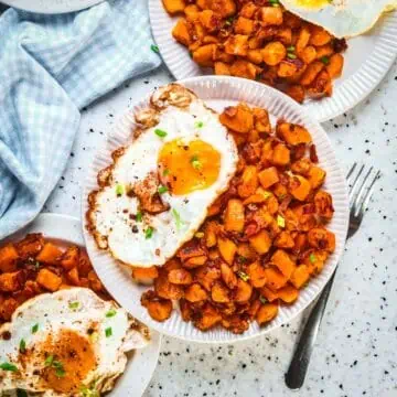 A plate of sweet potato hash with a sunny egg on the side.
