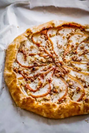 A baked pear and goat cheese galette on parchment paper.