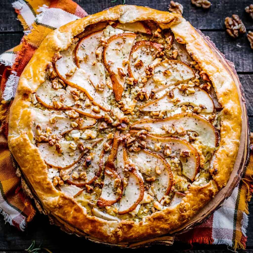 A pear galette with walnuts on a checkered orange napkin.