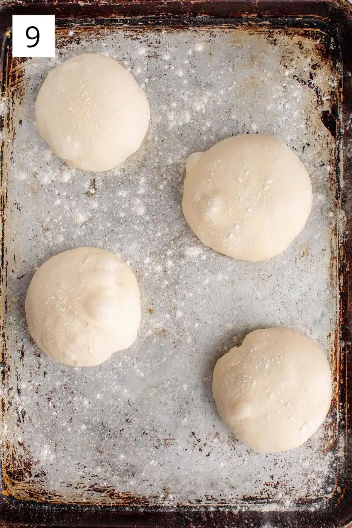 Small dough balls rising on a lined baking sheet.