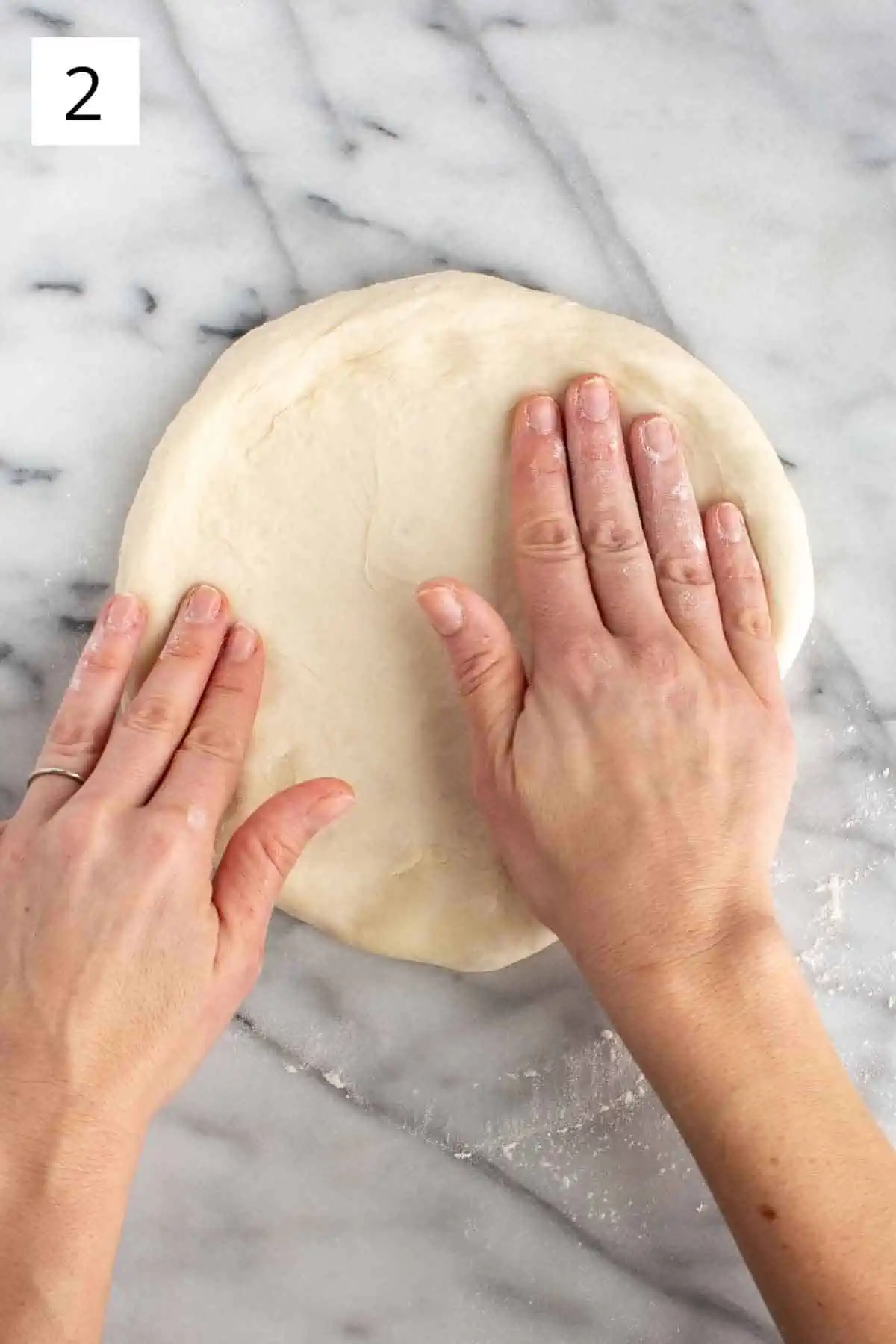 Pressing out pizza dough by hand.