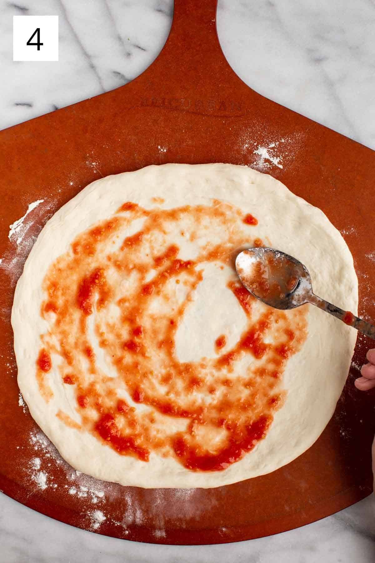 Spreading tomato sauce on pizza dough.