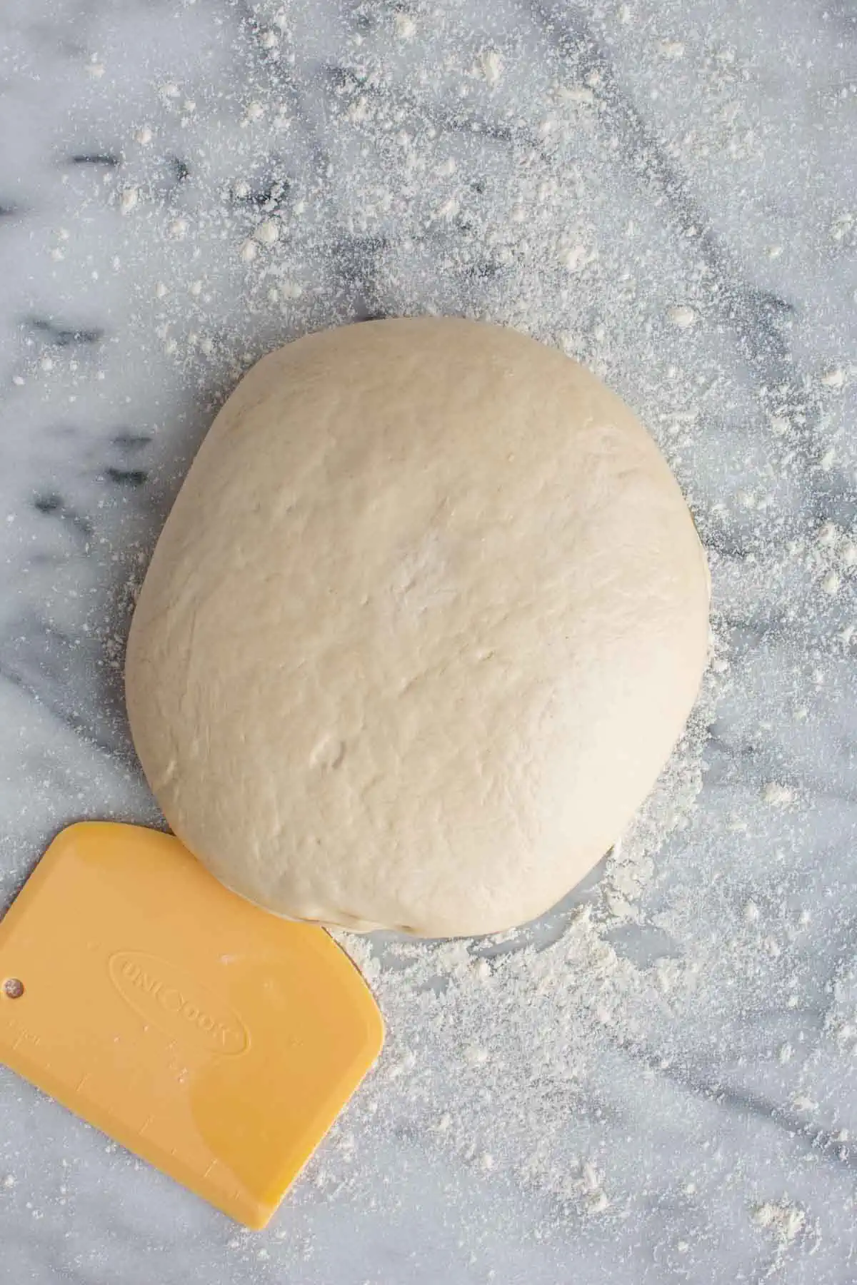 Large ball of pizza dough on a countertop.